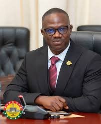 Ghanaian government official at desk reviewing documents, Ghana flag visible, documentary photography, data sovereignty